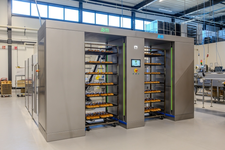 Geautomatiseerd ontladen van bakplaten met een industriële installatie.
